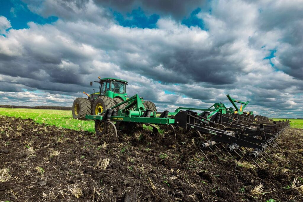 Tractor engaging in autumn-chisel plowing beneath a cloudy sky  