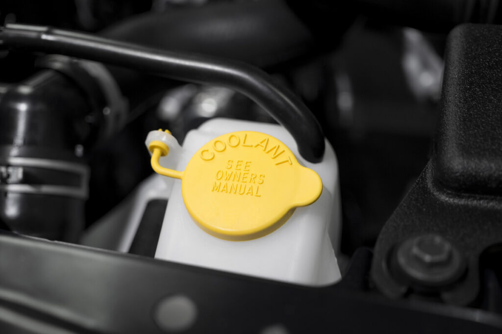 Bright yellow coolant reservoir cap prominently marked on a farm machinery engine