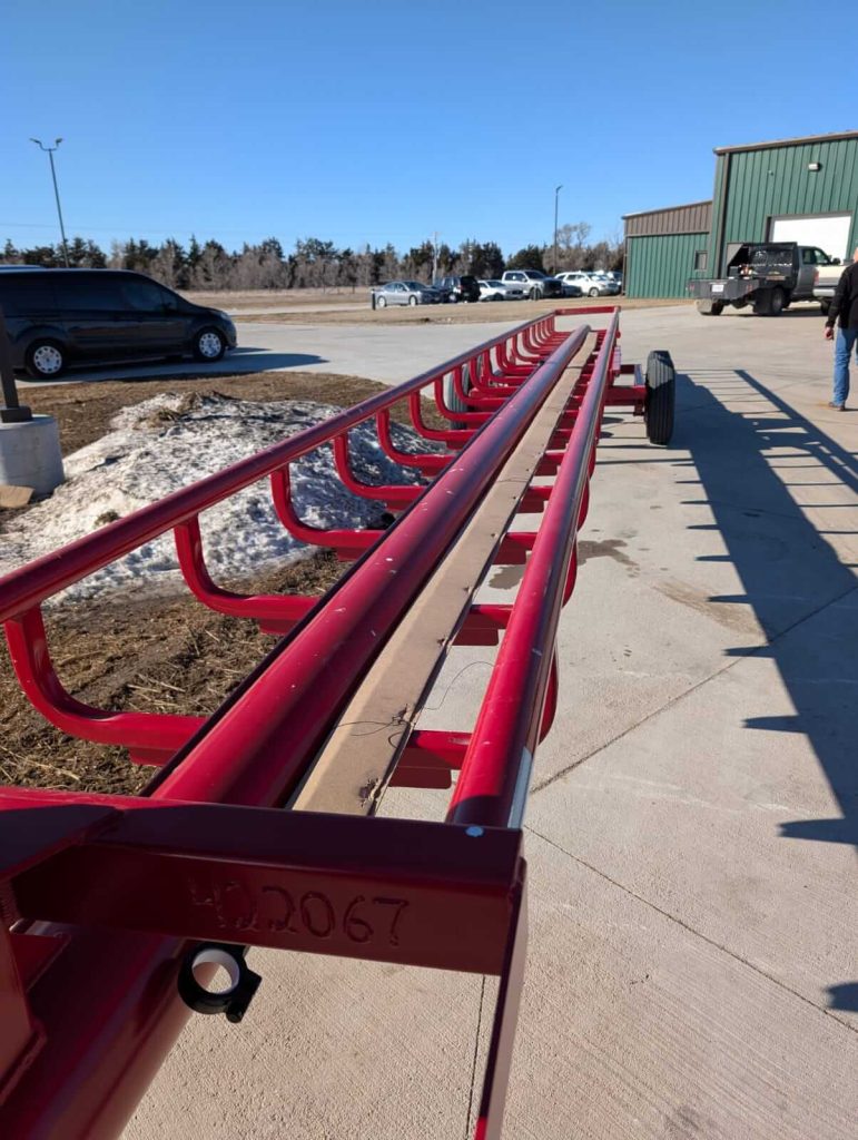 Red combine header trailer frame in farm equipment yard